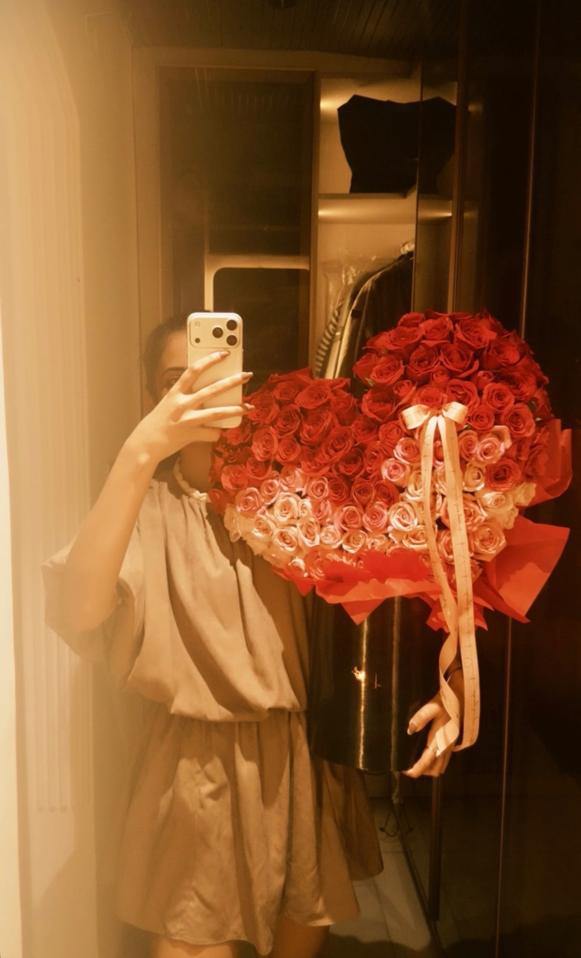 Client holding the AURA Rouge heart bouquet of red and blush roses